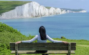 Woman sitting on deck chair by sea